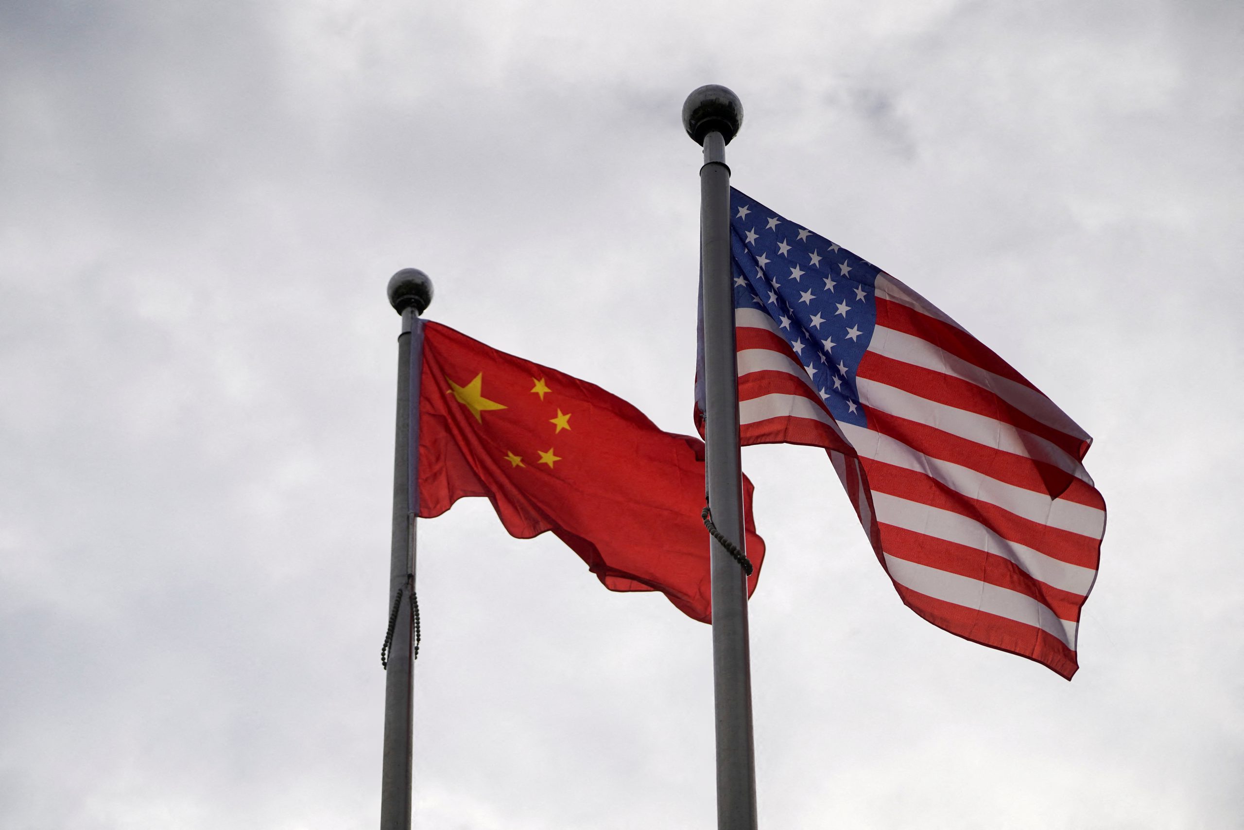 Chinese and U.S. flags flutter outside a company building in Shanghai, China November 16, 2021. REUTERS/Aly Song