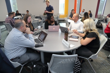 People seated around a table working on laptops.