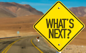 A road stretches out to an anticipatory horizon with a road sign asking what’s next