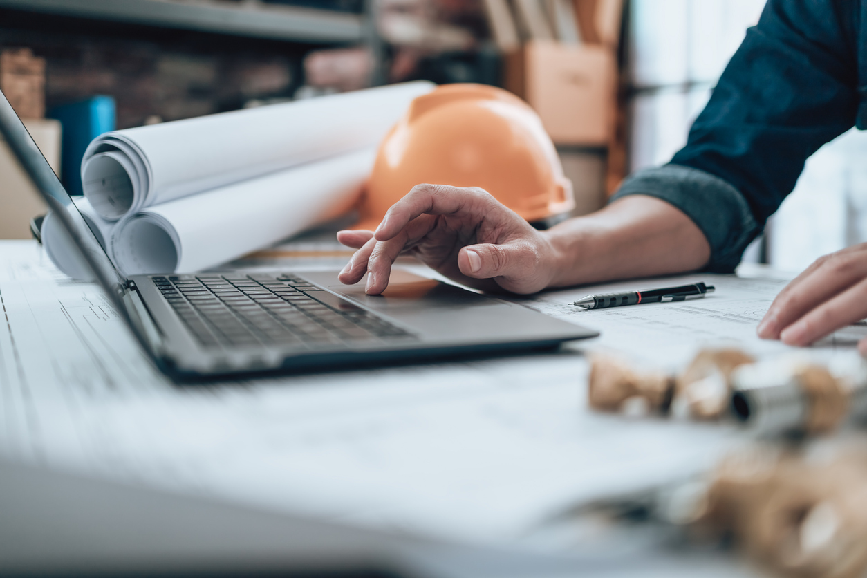 On a computer with design and construction plans on the table